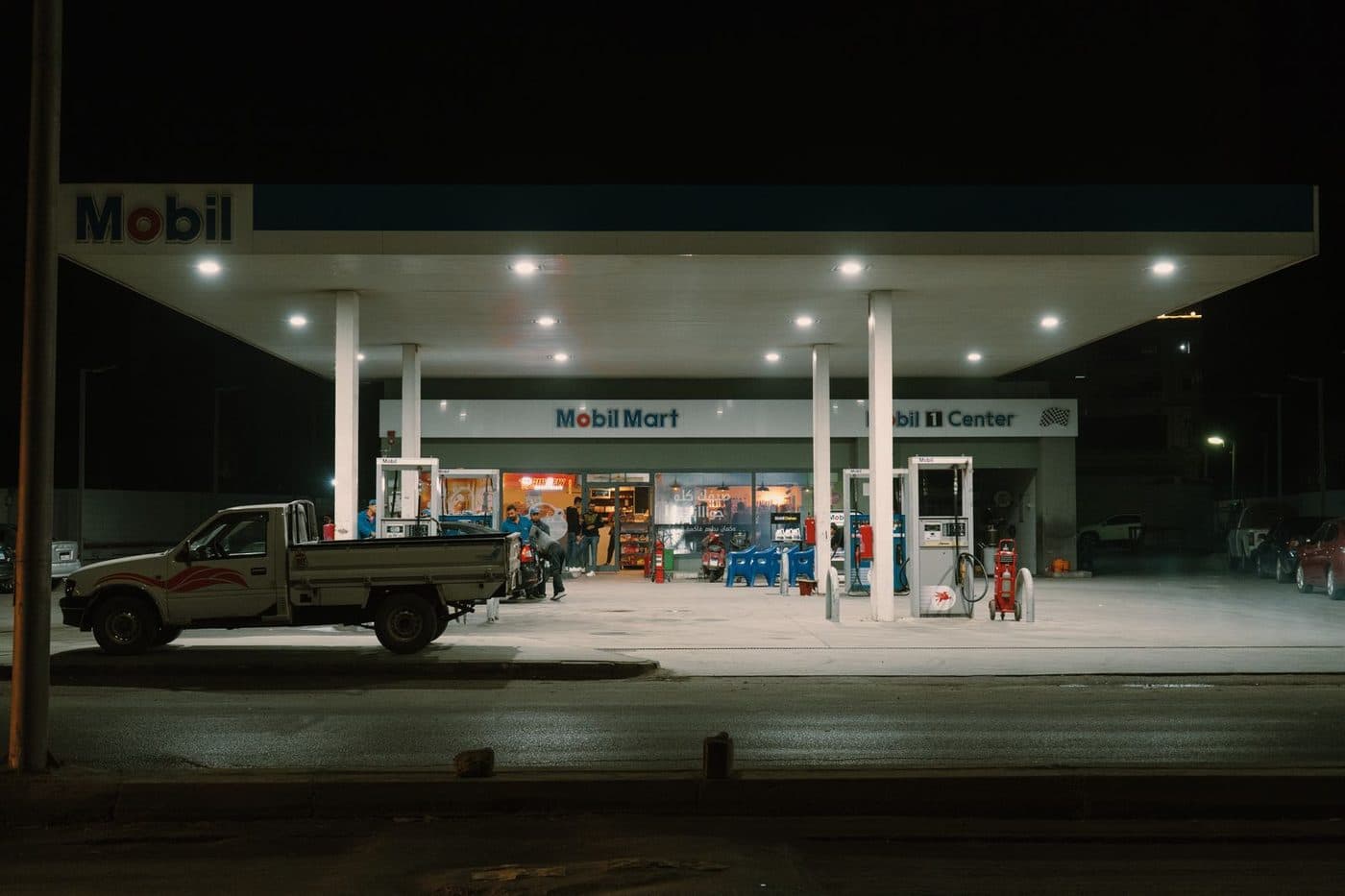A Mobil gas station lit up at night with customers at the pumps